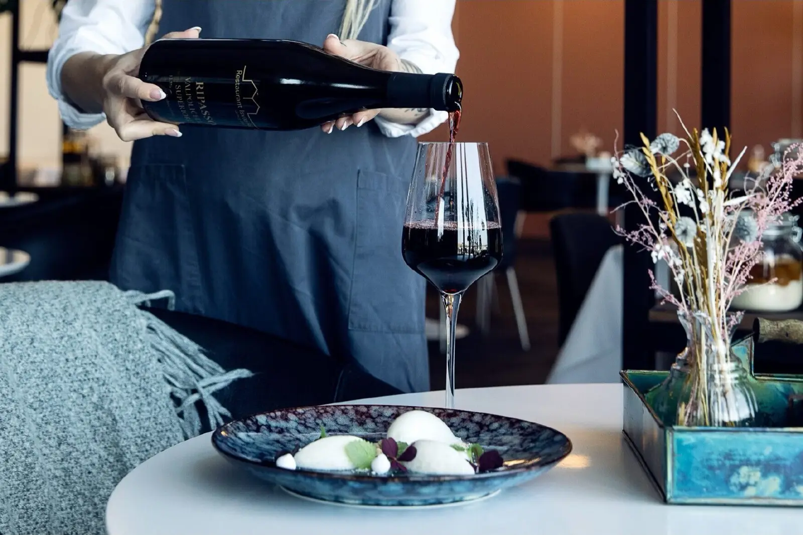 Serverer rødvin med dessert i restaurantmiljø.